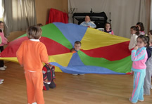 Nenos xogando cun paracaidas na clase de educación física.