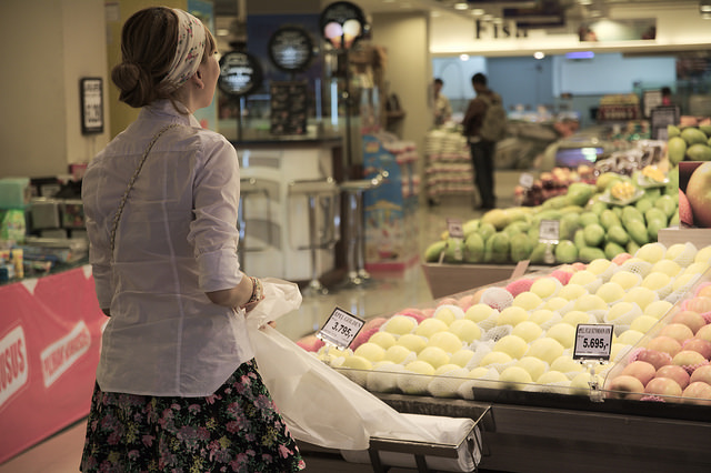 Imagen de una mujer preparándose para escoger la fruta en un supermercado