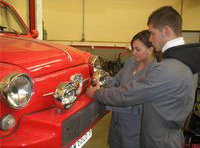 María y Lorenzo revisando el faro de un vehículo.
