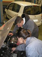 María y Lorenzo revisando el motor de un vehículo con capó gris.