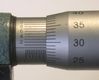 Detalle de un micrómetro, en el que se ve el tambor fijo  con su regla y el tambor móvil   con su nonio.