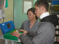 María y Lorenzo con un ordenador en un box de pintura.